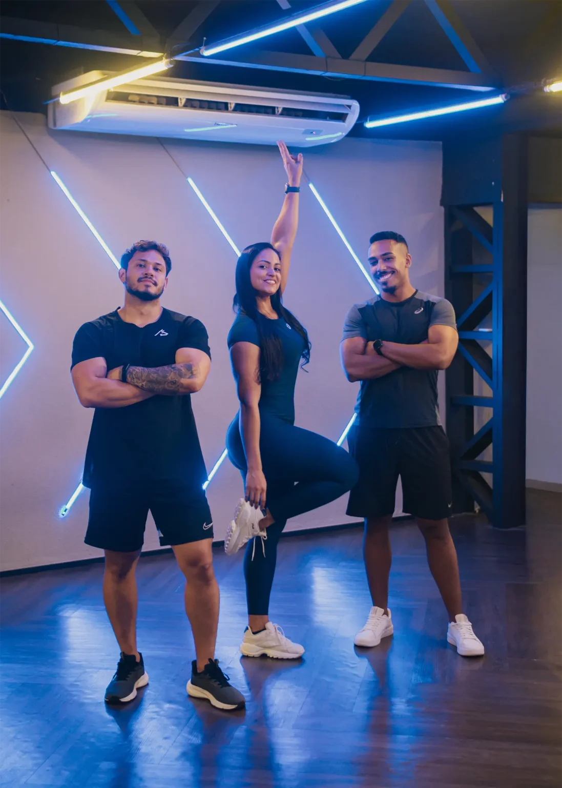 Três professores da Insano na sala de treino climatizada, com iluminação em neon azul